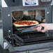 A hand taking a pizza out of a Merrychef eikon e4s rapid cook oven.