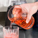 A person pouring a clear cocktail into a Libbey Carats cocktail stirring glass.