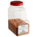 A clear plastic container with brown powder and a red lid.