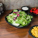 A bowl of salad and pasta in a black square bowl with scalloped edges.