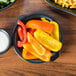 A Hall China round black au gratin dish filled with sliced peppers.