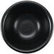 A close-up of a black Hall China sauce dish.