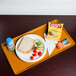 An orange Cambro dietary tray with a sandwich, chips, and a drink on it.
