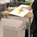 A person cutting vegetables on a Rubbermaid Slim Jim trash can lid.