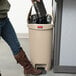 A woman using a Rubbermaid Slim Jim beige end step-on trash can.