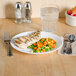 A plate of food with a chicken breast, vegetables, and a glass of water on a table.