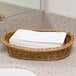 A wicker basket of Lavex Linen-Feel Royal paper guest towels on a counter.