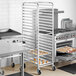 A woman putting cookies on a Regency sheet pan rack in a commercial kitchen.