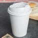 A white Dart Optima paper cup lid on a white coffee cup.