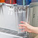 A hand using a Crathco Simplicity Bubbler cold beverage dispenser to fill a plastic cup.