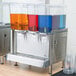 A Crathco refrigerated beverage dispenser with three different colored drinks.