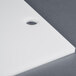 A white rectangular plastic filler plate with a black circle.