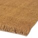 A close-up of a Cactus Mat natural tan cocoa brush scraper mat with fringes.