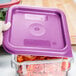 A person holding a purple Cambro square food storage container with a purple lid.