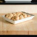 A Thunder Group Jazz rectangular melamine tray with a scalloped crackle-finished border holding rolls on a counter.