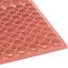 A red rubber floor mat with circular holes in it.