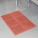 A red Cactus Mat TuffDek rubber floor mat with holes in it.