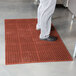 A person standing on a red Cactus Mat rubber floor mat.