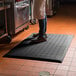 A person standing on a black Cactus Mat with drainage holes.