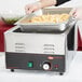 A person using a Hatco countertop food warmer to prepare fries.