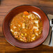A Tuxton Artisan Red Rock china soup bowl full of soup with vegetables.