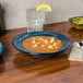 A Tuxton TuxTrendz Artisan Night Sky china soup bowl on a table with a bowl of soup and a plate of salad.