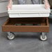 A person holding a white Cambro pizza dough box on a brown cart.