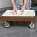 A person holding a tray of pizza dough.