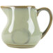 A close-up of a Tuxton Artisan Sagebrush China creamer with a handle.