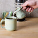 A person pouring milk into a cup of coffee on a table.