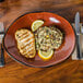 A Tuxton Artisan Red Rock china plate with a lemon slice and rice on it.