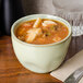 A close-up of TuxTrendz Sagebrush China Bouillon filled with food on a table.