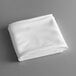 A folded white Intedge round cloth table cover on a gray surface.