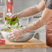 A person in Royal Paper elbow length plastic gloves preparing salad.