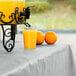 A glass of orange juice sits on a table with a Shimmering Silver table cover.