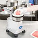 A person using a Globe hamburger press to make a patty from ground meat.