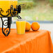 A glass of orange juice on a Sunkissed Orange table cover.
