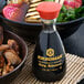 A bottle of Kikkoman soy sauce next to a bowl of food.