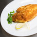 A plate of fried fish with lemon wedges on a table with Kikkoman Panko bread crumbs.