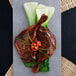 A plate of food including chicken legs and vegetables with Kikkoman Tamari Soy Sauce on the table.