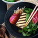 A bowl of Kikkoman Tamari soy sauce on a plate of Asian food with chopsticks.