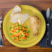 A piece of bread on a Fiesta® Sunflower china plate with a fork and knife.