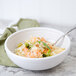 A Fiesta medium white china bowl filled with pasta, shrimp, and broccoli with a spoon in it.