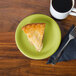 A slice of pie on a green Fiesta® appetizer plate next to a cup of coffee.