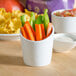 A close-up of a white Tuxton bowl filled with vegetables and chips.