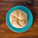 A turquoise Fiesta bread and butter plate with a piece of bread on it.