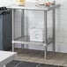 A metal table with a Regency stainless steel undershelf holding a white plastic container with blue writing.