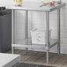 A metal Regency work table with an undershelf holding a white plastic container.