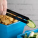 A hand using Fineline black plastic serving tongs to cut a cucumber slice.