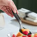 A black plastic serving spoon being used to serve fruit.